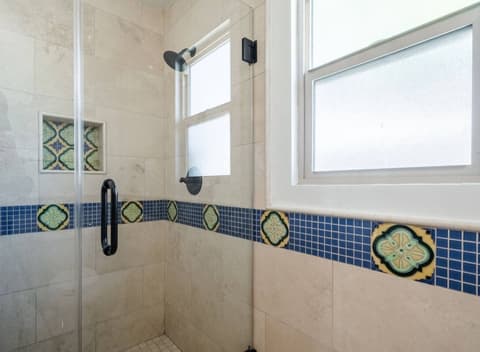 An efficient and well-lit bathroom, with a generously sized shower thoughtfully crafted to maximize guest comfort.
