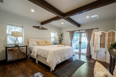 Generous bedroom drenched in natural light, featuring a cozy double bed, breathtaking outdoor vistas, and a full range of amenities for an utterly rejuvenating experience.