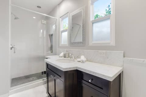 An efficient and well-lit bathroom, with a generously sized shower thoughtfully crafted to maximize guest comfort.