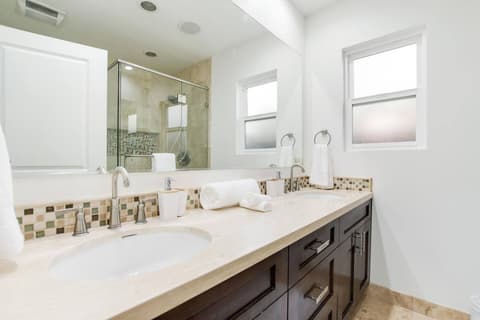 An efficient and well-lit bathroom, with a generously sized shower thoughtfully crafted to maximize guest comfort.